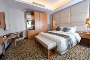 ein Hotelzimmer mit einem großen Bett und einem Schreibtisch in der Unterkunft Grand Park by VERTA in Dschidda