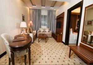 um quarto de hotel com uma secretária e uma sala de estar em Grand Park by VERTA em Jeddah