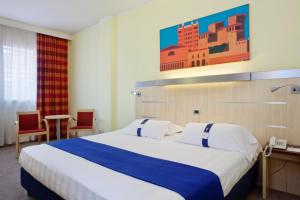 a hotel room with a large bed and two chairs at Holiday Inn Express Parma, an IHG Hotel in Parma