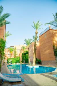 Riad The Moroccans Pool And Terrace في مراكش: مسبح بالنخيل بجانب مبنى