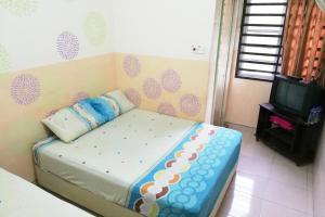 una piccola camera da letto con un letto e una TV di Kampung Homestay, Kuantan a Kuantan