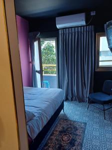 um quarto com uma cama, uma cadeira e uma janela em Ninna palatin em Haifa