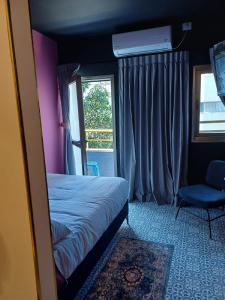 a bedroom with a bed and a chair and a window at Ninna Palatin in Haifa