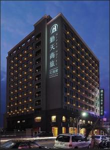un bâtiment d'hôtel avec des voitures garées dans un parking dans l'établissement HiYesHotel勤天商旅-花蓮館, à Hualien