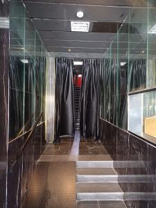 un couloir avec des rideaux noirs et des escaliers dans un bâtiment dans l'établissement Ninna palatin, à Haïfa