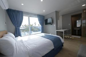 a bedroom with a large bed and a window at Sweet Stay Pension in Seogwipo