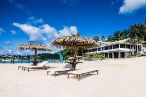 zwei Stühle und zwei Sonnenschirme am Strand in der Unterkunft Iririki Island Resort & Spa in Port Vila