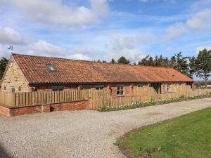 a brick barn with a wooden fence in front of it at Beth's Cottage in Malton