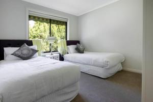 um quarto branco com 2 camas e uma janela em Adelaide Hills 4 bed home near Hahndorf Mt Barker 