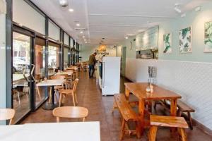 a restaurant with tables and chairs and a man in the background at 1 Bedroom Apt with Parking Pool and Gym in Sydney