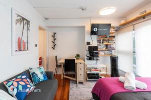 a living room with a couch and a desk at Studio Gem With Rooftop Space Prime Location in Sydney