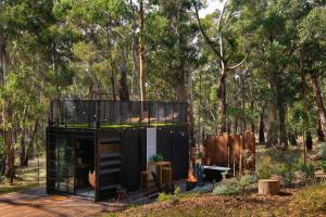 una casa negra en medio de un bosque en Musk See Tiny Home, en Bullarto