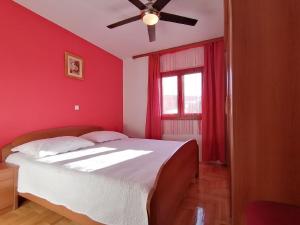 Schlafzimmer mit einem Bett mit roten Wänden und einem Deckenventilator in der Unterkunft Ferienhaus für 7 Personen und 1 Kind in Jasenice, Dalmatien Norddalmatien in Jasenice