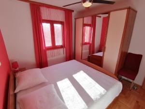 Schlafzimmer mit einem Bett mit roten Wänden und einem Fenster in der Unterkunft Ferienhaus für 7 Personen und 1 Kind in Jasenice, Dalmatien Norddalmatien in Jasenice