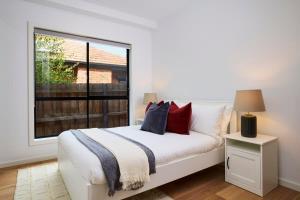 1 dormitorio con cama blanca y ventana grande en 5 Bedroom 5 Bathroom Townhouse with Aircon en Melbourne
