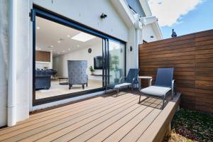 una terraza de madera con 2 sillas y una mesa en 5 Bedroom 5 Bathroom Townhouse with Aircon, en Melbourne
