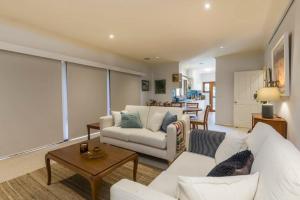 ein Wohnzimmer mit einem weißen Sofa und einem Tisch in der Unterkunft 3 Bdrm 2 Bthrm House Close to Canberra CBD & ANU in Canberra