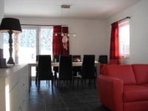 sala de estar con sofá rojo, mesa y sillas en Ferienhaus für 10 Personen in Slupecna, Böhen Moldau, en Lipno nad Vltavou