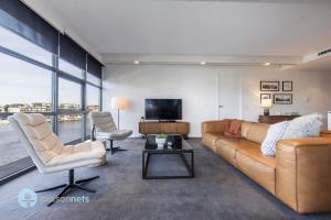 キャンベラにあるModern 2 Bdrm Apt with Water Views 2x Car Spotsのソファと椅子とテレビのあるリビングルーム