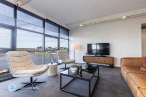 sala de estar con sofá, sillas y TV en Modern 2 Bdrm Apt with Water Views 2x Car Spots en Canberra
