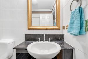 a bathroom with a sink and a mirror and a toilet at Cozy Studio in Historic Brisbane CBD in Brisbane
