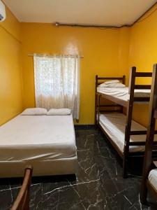 Duas camas num quarto com paredes amarelas e uma janela em Hotel Music and Sports em São Paulo
