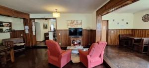 a living room with red chairs and a table and a tv at Posada del Ñireco in San Carlos de Bariloche