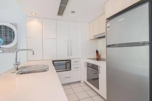 a white kitchen with a sink and a refrigerator at Echelon Apartments Yeppoon in Yeppoon