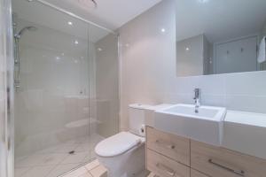a bathroom with a toilet and a shower and a sink at Echelon Apartments Yeppoon in Yeppoon