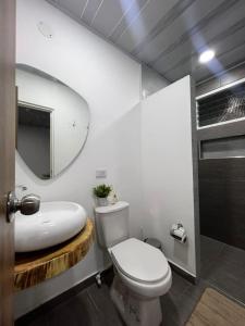 ein Badezimmer mit einem WC, einem Waschbecken und einem Spiegel in der Unterkunft Casa Ambrosía in Calarcá