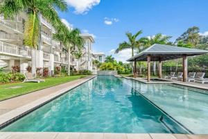 a swimming pool in front of a building with a gazebo at Marina Living with views and more in Airlie Beach