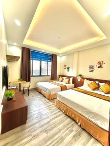 una camera d'albergo con 2 letti e una scrivania di Khách sạn Xanh Tốt FLC Sầm Sơn a Sầm Sơn
