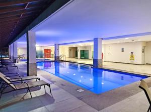 a swimming pool with chairs in a building at FLAT VARANDA PEDRA AZUL - Vista Azul Apart Hotel in Pedra Azul