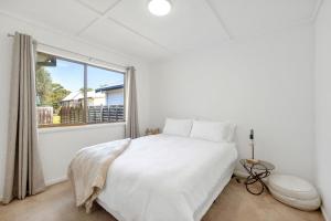 a bedroom with a white bed and a large window at Jacaranda Cottage at the Beach in Cowes