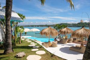 um resort com piscina e guarda-sóis de palha em Le Pirate Beach Club Nusa Ceningan - Adults Only em Nusa Lembongan