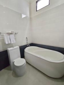a white bathroom with a tub and a toilet at Hotel Harmony In & Karaoke in Pontianak