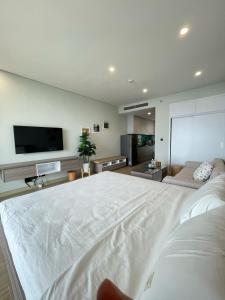 Cette chambre comprend un grand lit blanc et une télévision à écran plat. dans l'établissement Comzy Ha Long Homestay, à Hạ Long