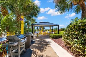 a grill and a gazebo at a resort with palm trees at South Beach Condo Hotel by Travel Resort Services, Inc. in St Pete Beach