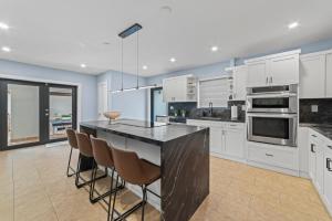 una cucina con mobili bianchi e un piano di lavoro nero di Miami House Pool Game Room BBQ L24 a Miami Gardens