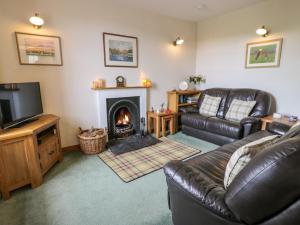 a living room with a couch and a fireplace at Craggs Cottage in Smailholm