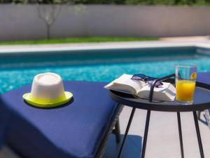 un sombrero y un libro sobre una mesa con un vaso de zumo de naranja en Ferienhaus für 10 Personen in Loborika, Istrien Südküste von Istrien en Loborika