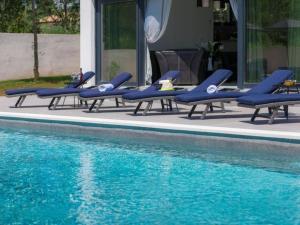 - une rangée de chaises longues bleues à côté de la piscine dans l'établissement Ferienhaus für 10 Personen in Loborika, Istrien Südküste von Istrien, à Loborika