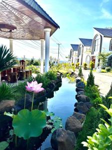 um jardim com um lago com lírios e uma casa em Ellieza Motel em Môndól Kiri