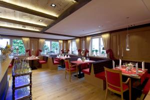 Sandebeck的住宿－Germanenhof，餐厅设有桌子和红色椅子以及窗户。