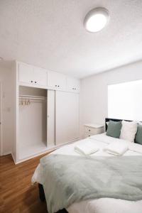 a white bedroom with a large bed and a light at ModernHaven -SoFi, Forum, Intuit in Hawthorne