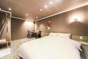 a bedroom with a large white bed and a desk at Tinto Hotel in Busan