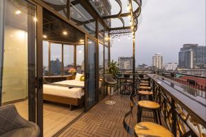 Habitación con balcón con 1 cama y sillas. en Light House & Rooftop en Hanoi