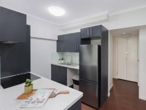 a kitchen with black cabinets and a stainless steel refrigerator at Stunning 2BR Beachfront Retreat in North Ward