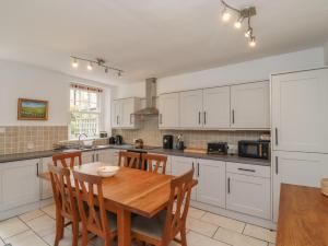 a kitchen with white cabinets and a wooden table at Avocet Cottage in Bamburgh