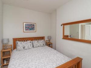 a bedroom with a bed and a mirror at Avocet Cottage in Bamburgh